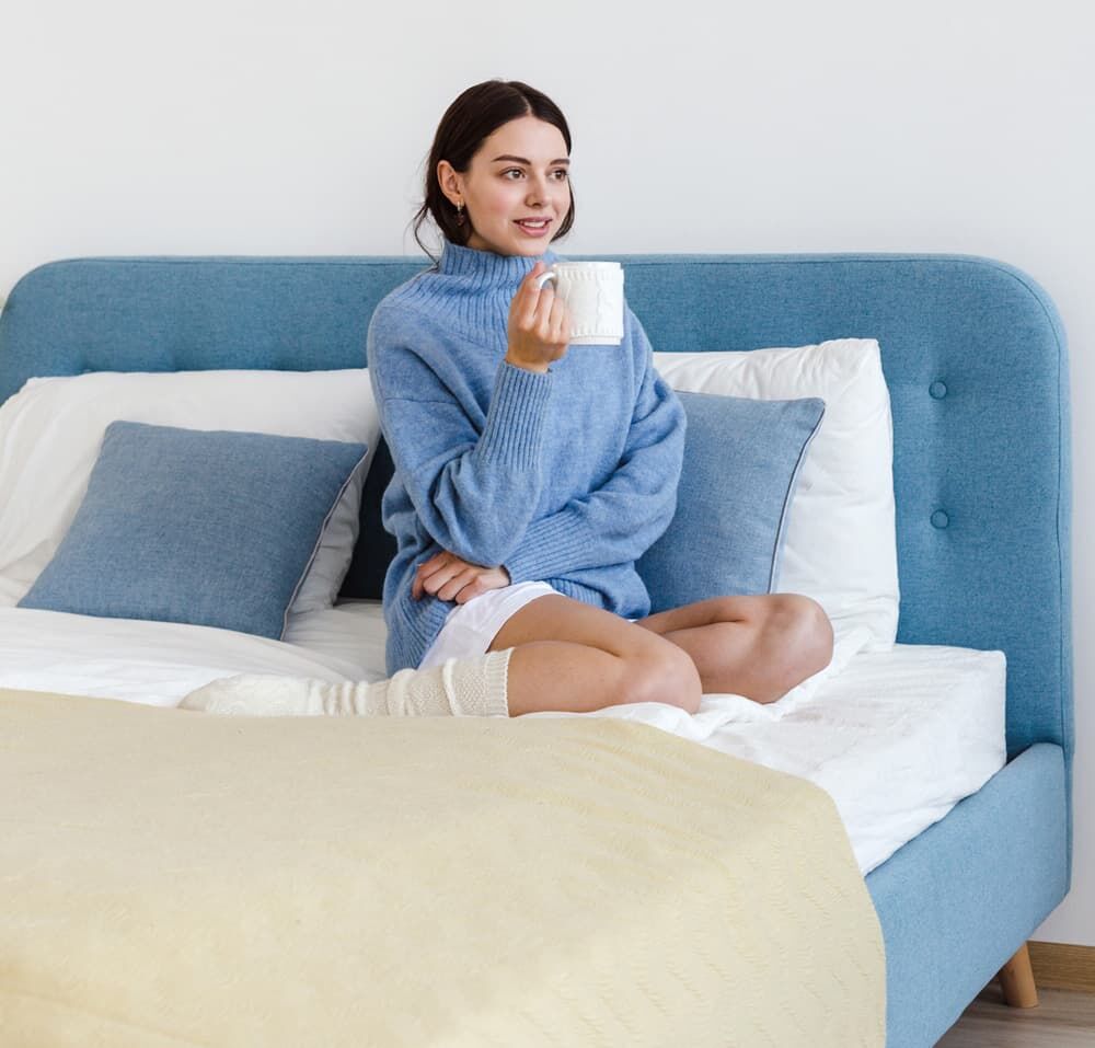 Frau sitzt im Bett auf Matratze