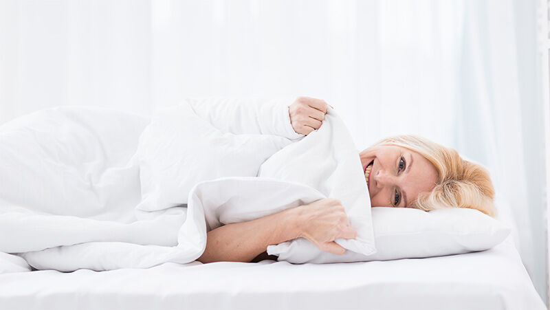 Frau liegt entspannt im Bett